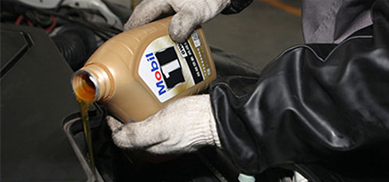 mechanic pouring mobil 1 oil into car engine